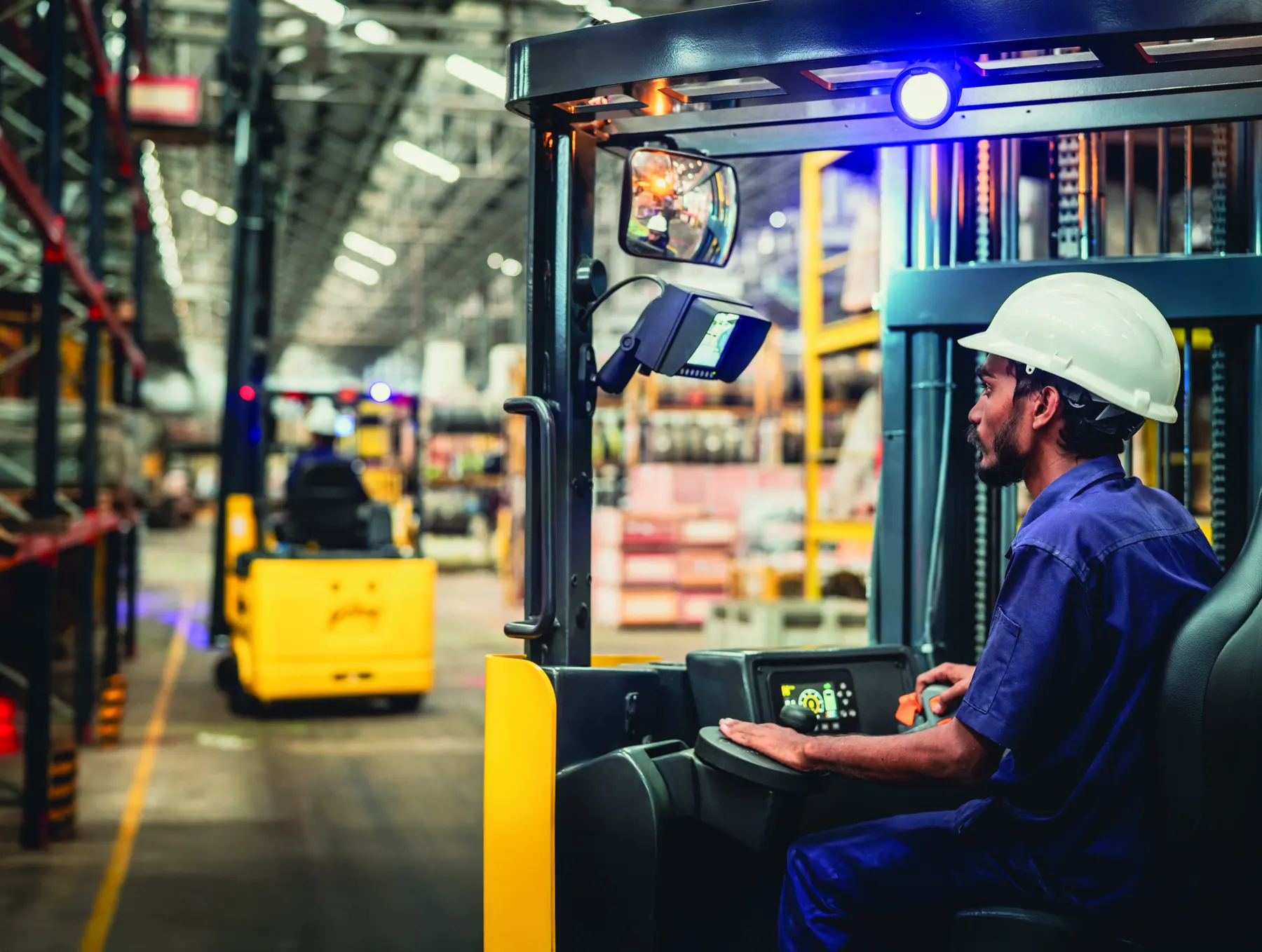 An operator at the controls of a Godrej forklift in a warehouse